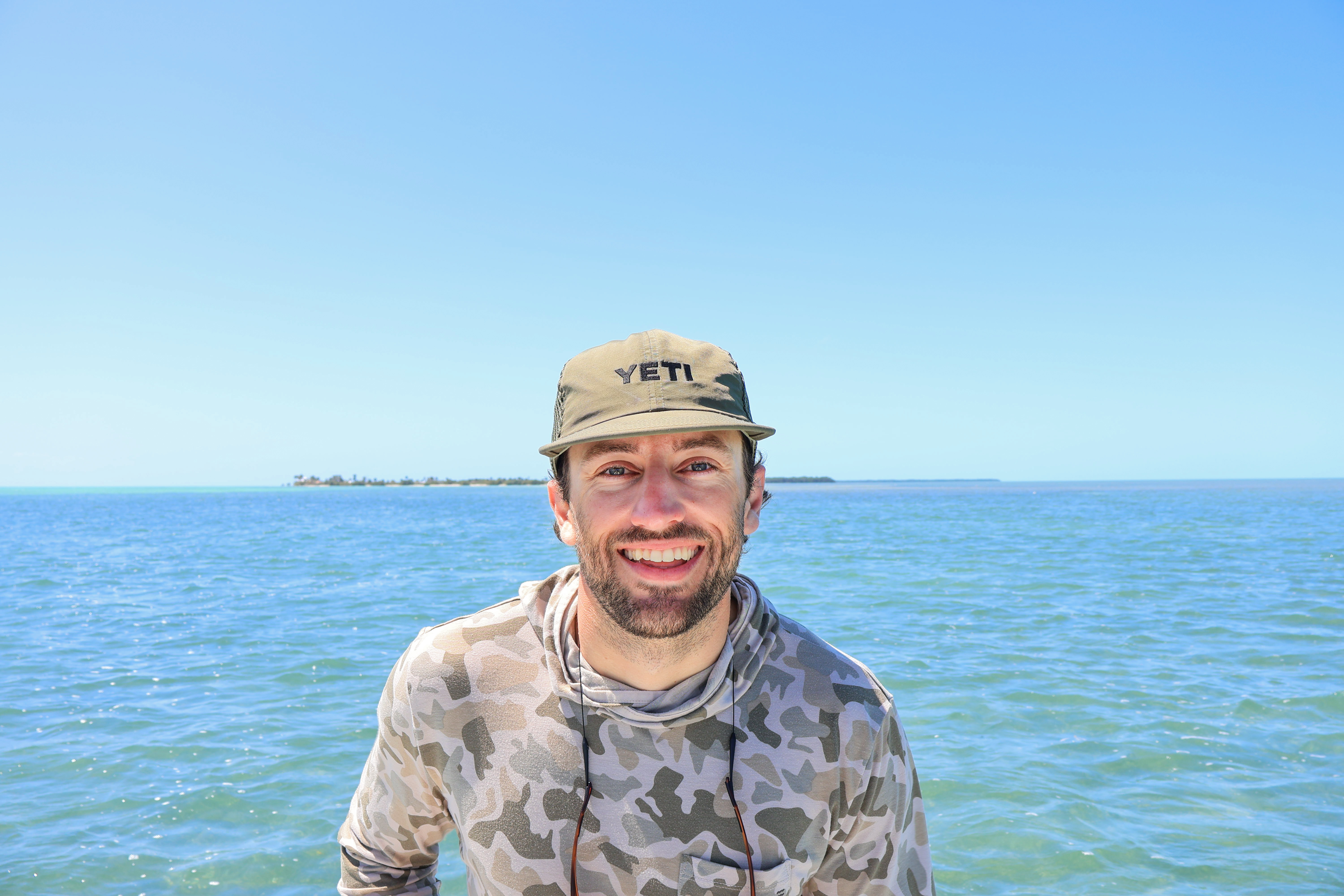 Jack Shirk, founder of Flood Tide Digital, smiling on the water in a fishing shirt and cap
